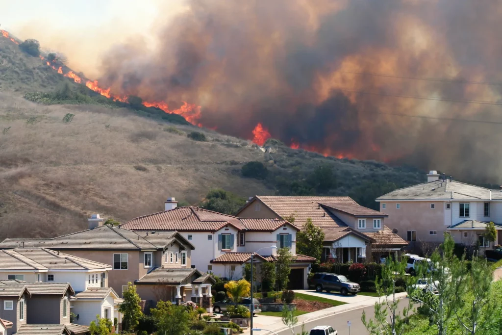 A wildfire burning a mountain with homes nearby. 